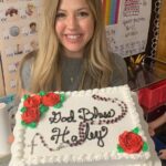 female teacher holding a cake and smiling